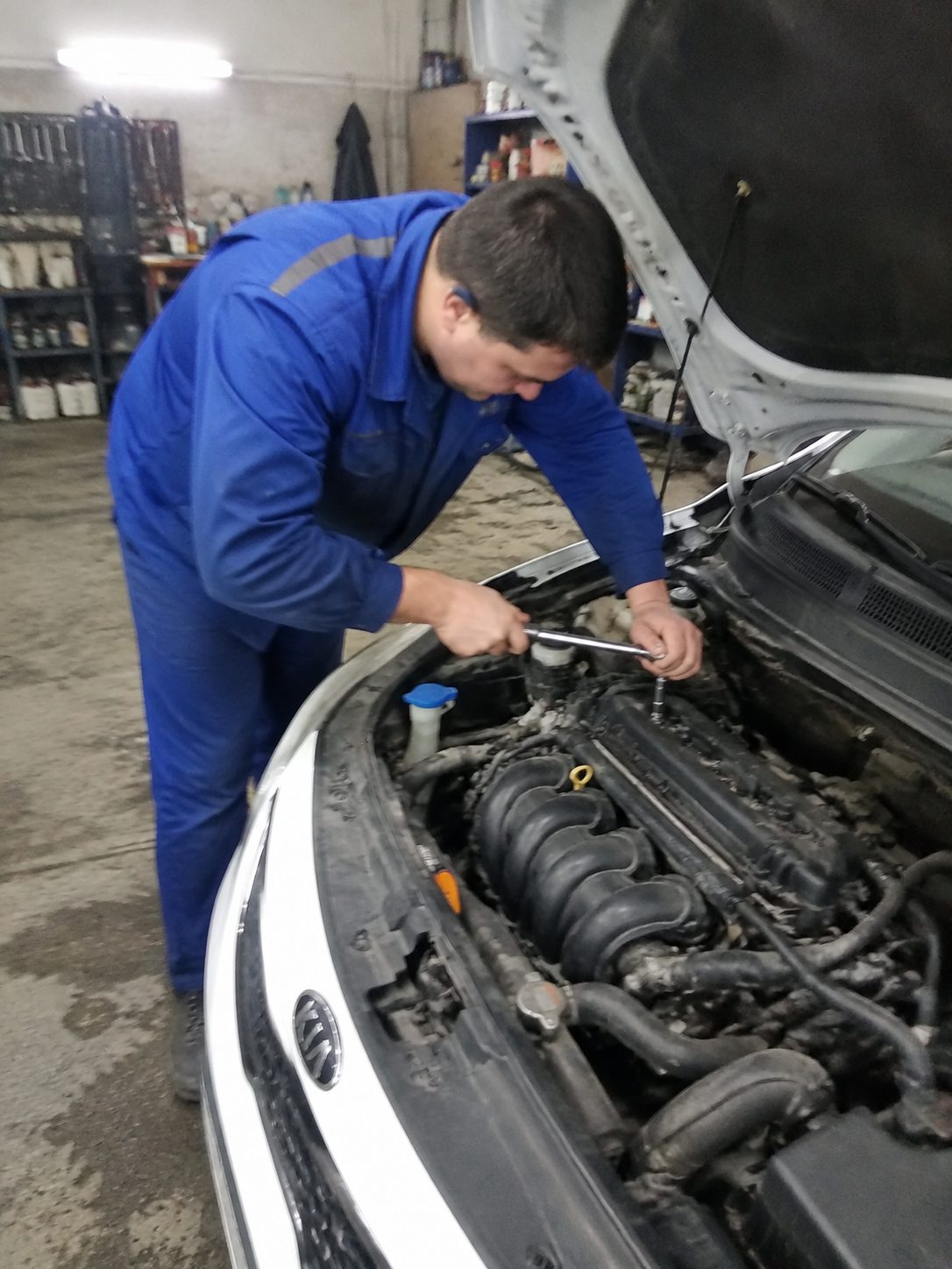 Мастер у открытого капота KIA